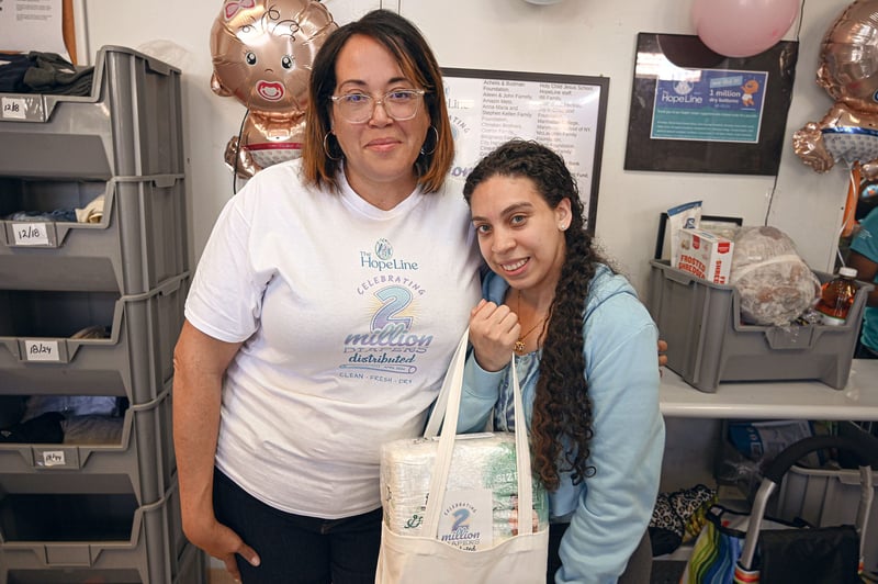 HopeLine Executive Director Maria Cintron with client, Jessica holding bag of diapers.