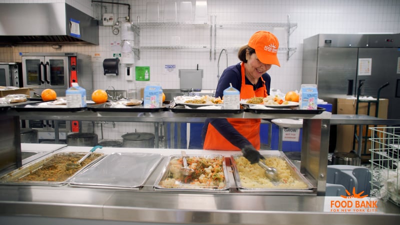 Volunteer serves meals at Food Bank For New York City's Community Kitchen in Harlem. 