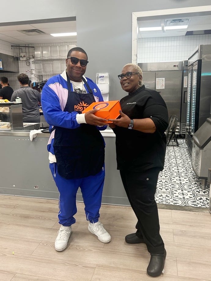 Kenan Thompson receives chocolate chip cookies at Food Bank For New York City Community Kitchen.